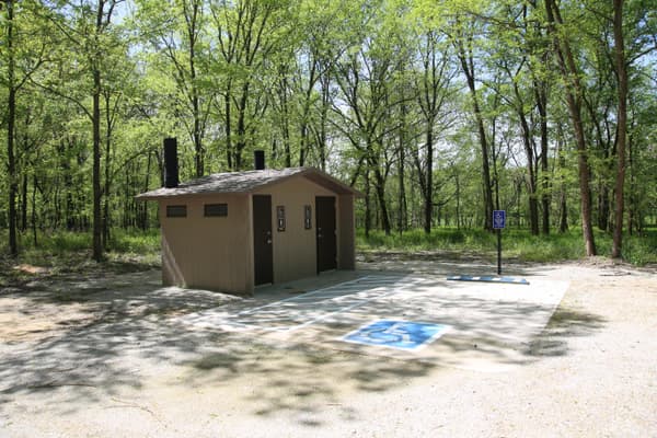 A concrete vault toilet building along the edge of a forest. - NPS Photo / Wil Marischen