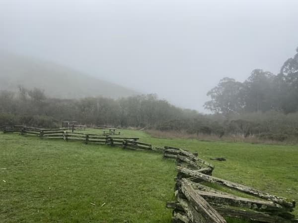 A low wooden fence separates green grass. - Lara Volski NPS