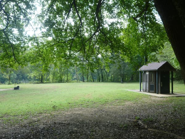Vault restroom facility in Rush Campground with shade trees nearby. - NPS