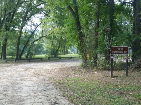 Rush Campground entrance sign and gravel parking lot. - NPS