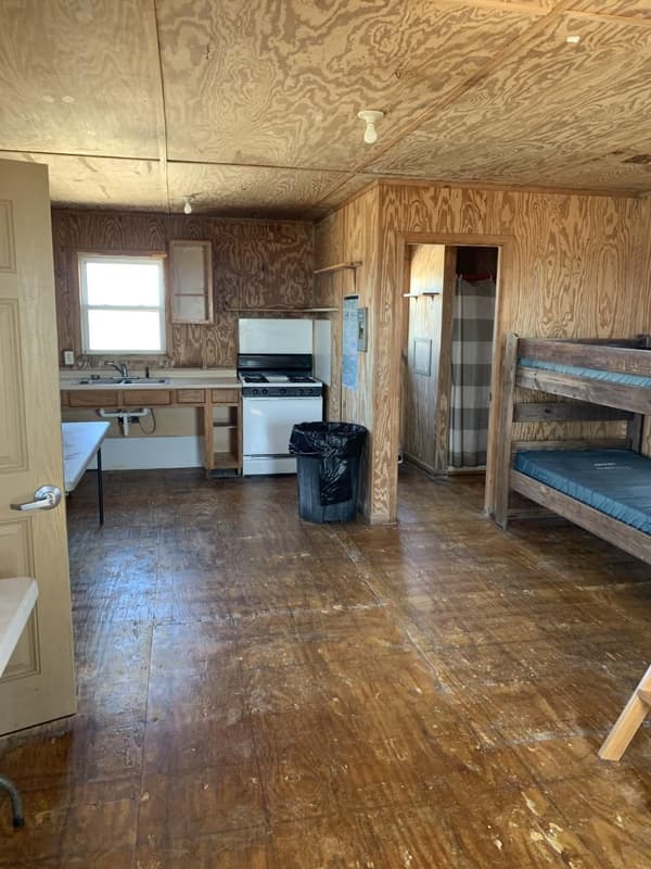Rustic cabin interior showing bunk beds, kitchenette and doorway to restroom - NPS photo/Jan Tugwell