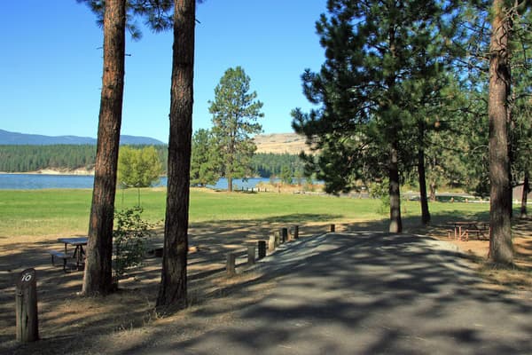 paved campsite parking area with lake in background - NPS Photo