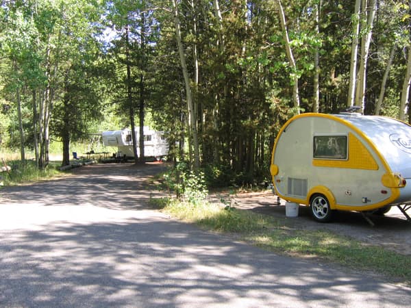 two small white trailers at campsites with conifers surrounding them - NPS Photo / A. Mattson