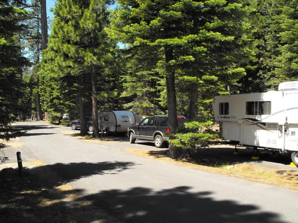 A paved road lined by campsites containing trailers and vehicles. - NPS Photo